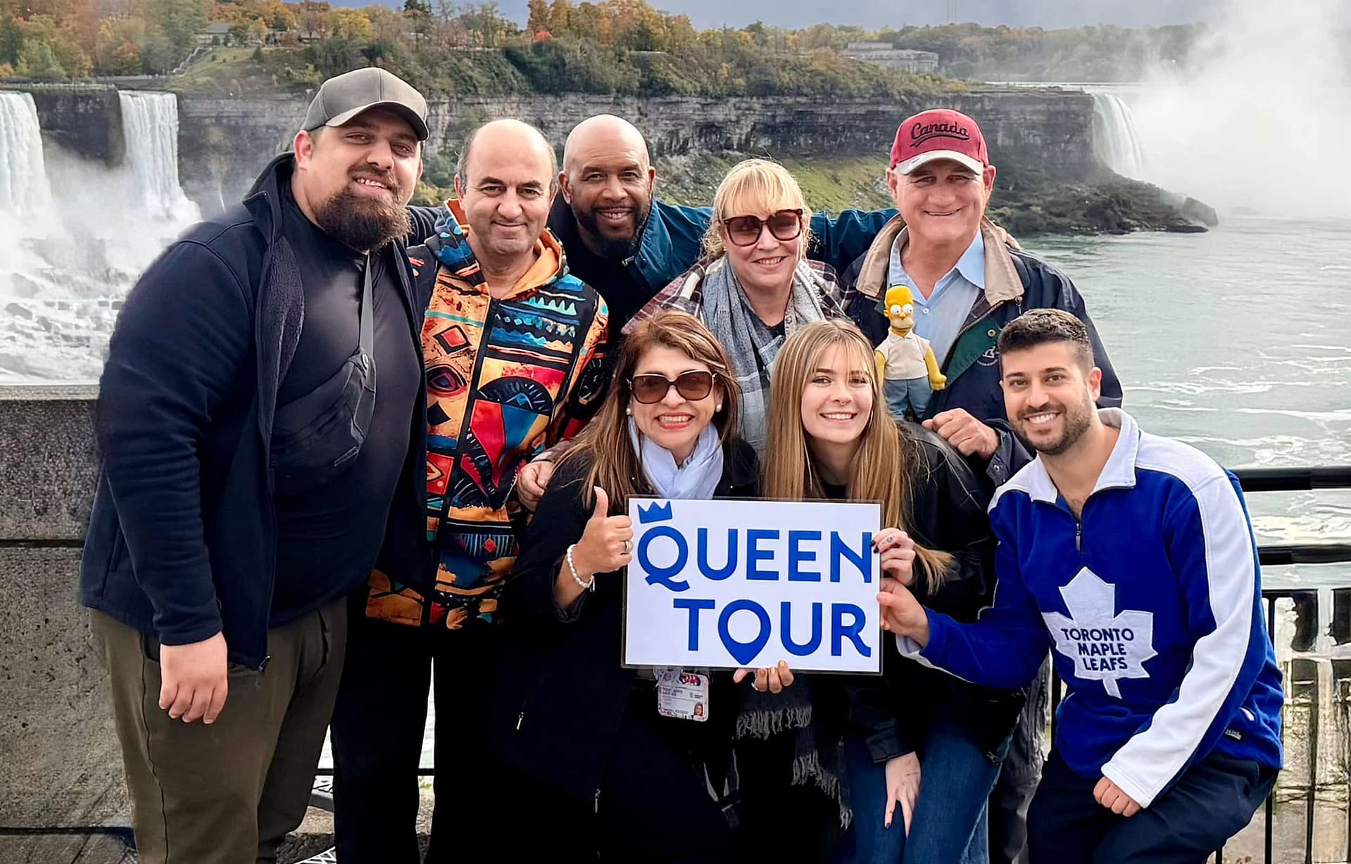 Private tour group holding a Queen Tour sign in front of Niagara Falls